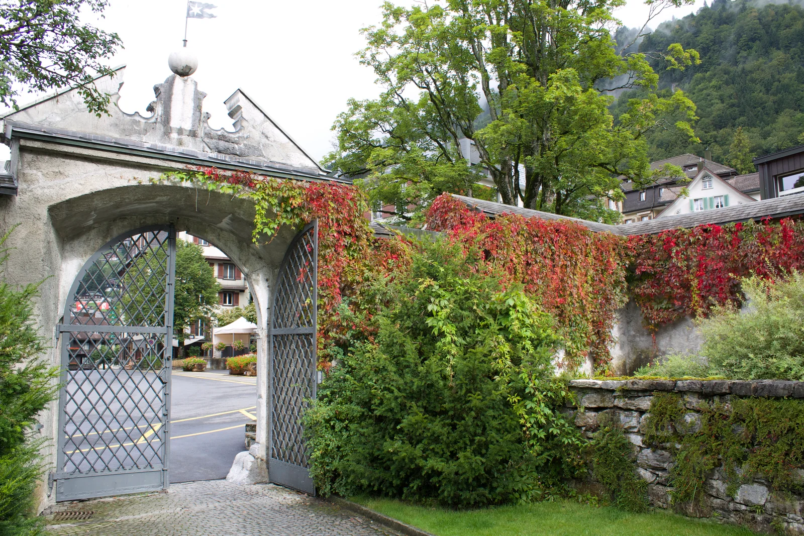 A leafy stone gateway and Swiss village buildings in Engelberg