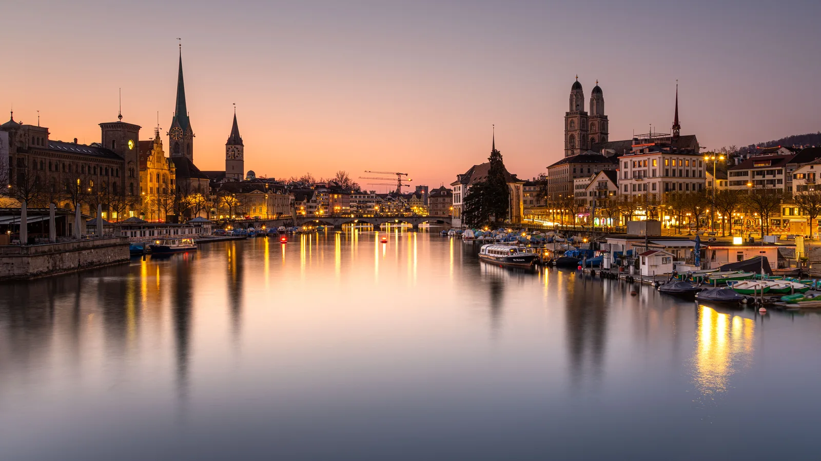 Zurich old town and church towers reflected in the Limmat River at sunset